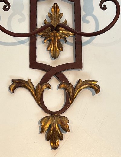 Coppia di applique in ferro battuto e legno rosso antico con foglie d'acanto dorate.