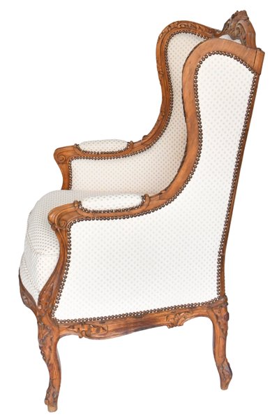 Fauteuil bergère à oreilles de style Louis XV en bois richement sculpté