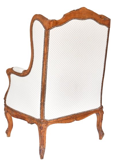 Fauteuil bergère à oreilles de style Louis XV en bois richement sculpté