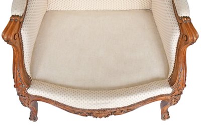 Fauteuil bergère à oreilles de style Louis XV en bois richement sculpté