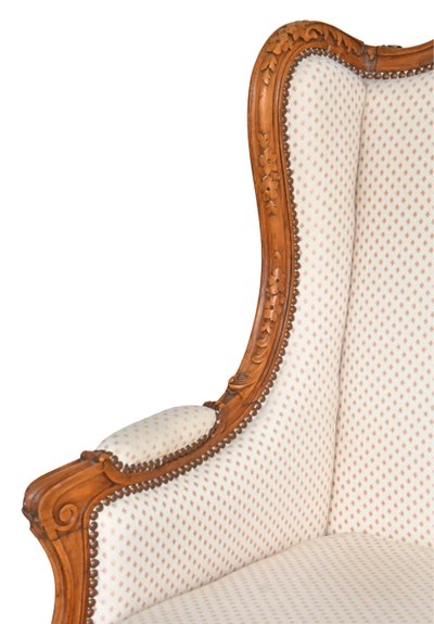 Fauteuil bergère à oreilles de style Louis XV en bois richement sculpté