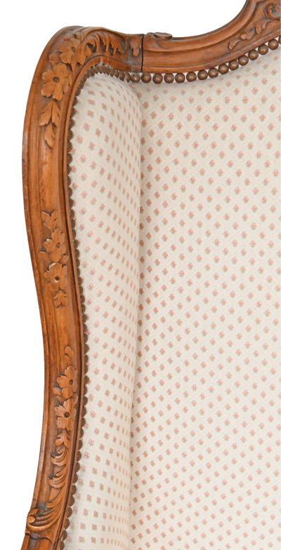 Fauteuil bergère à oreilles de style Louis XV en bois richement sculpté