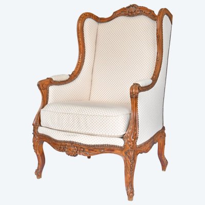 Fauteuil bergère à oreilles de style Louis XV en bois richement sculpté