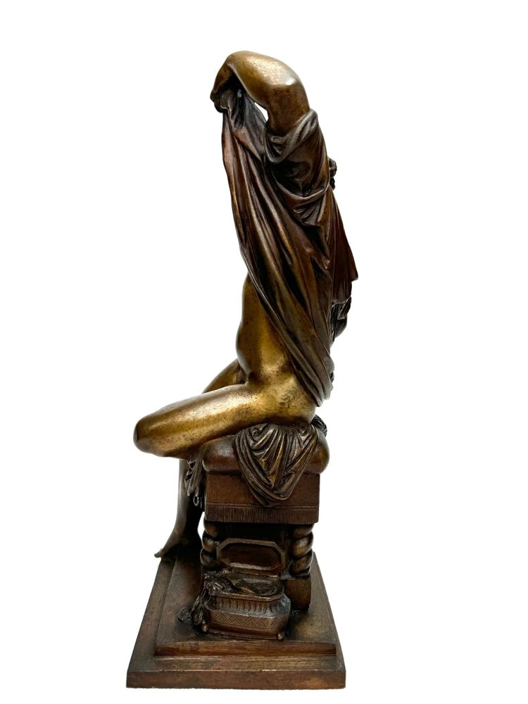 Scultura in bronzo raffigurante una donna seduta che si spoglia