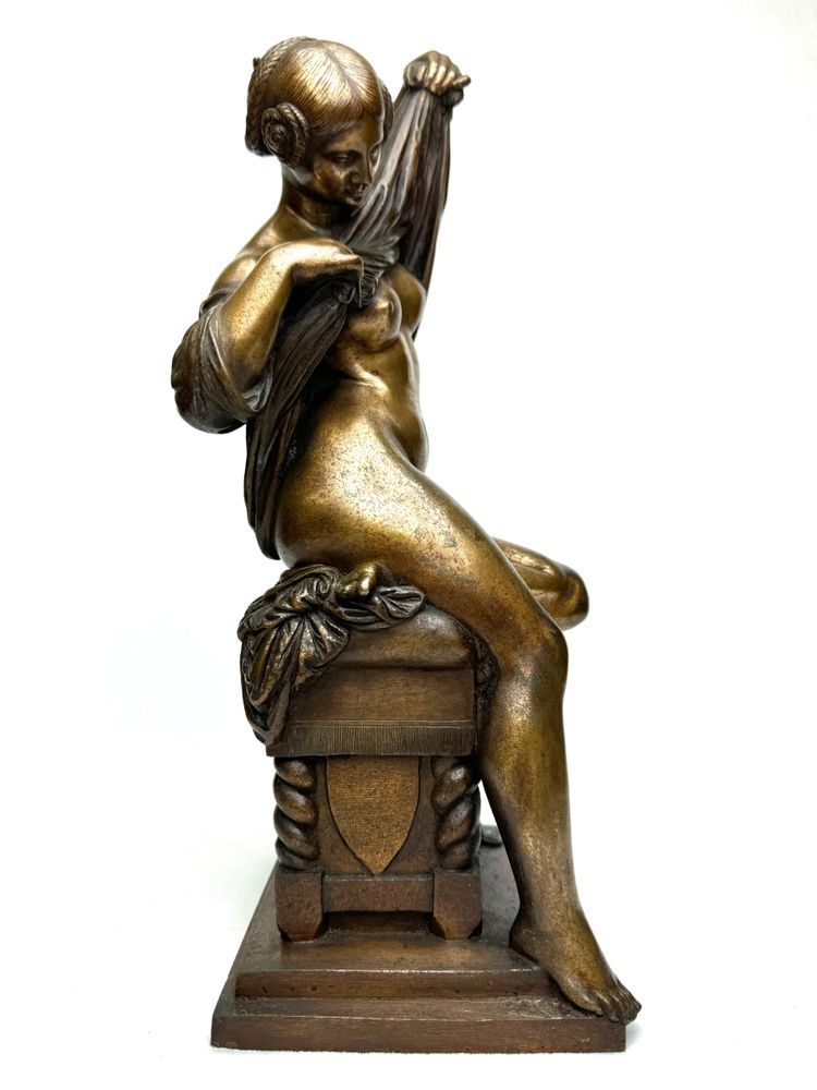 Scultura in bronzo raffigurante una donna seduta che si spoglia