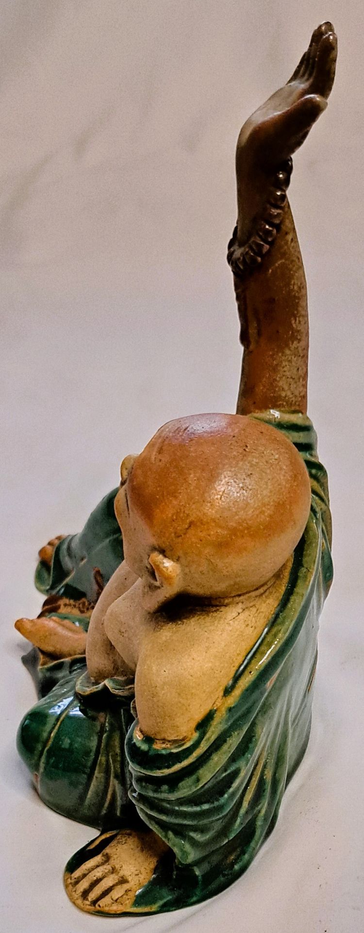 Antica statua di Buddha in terracotta con un braccio sollevato