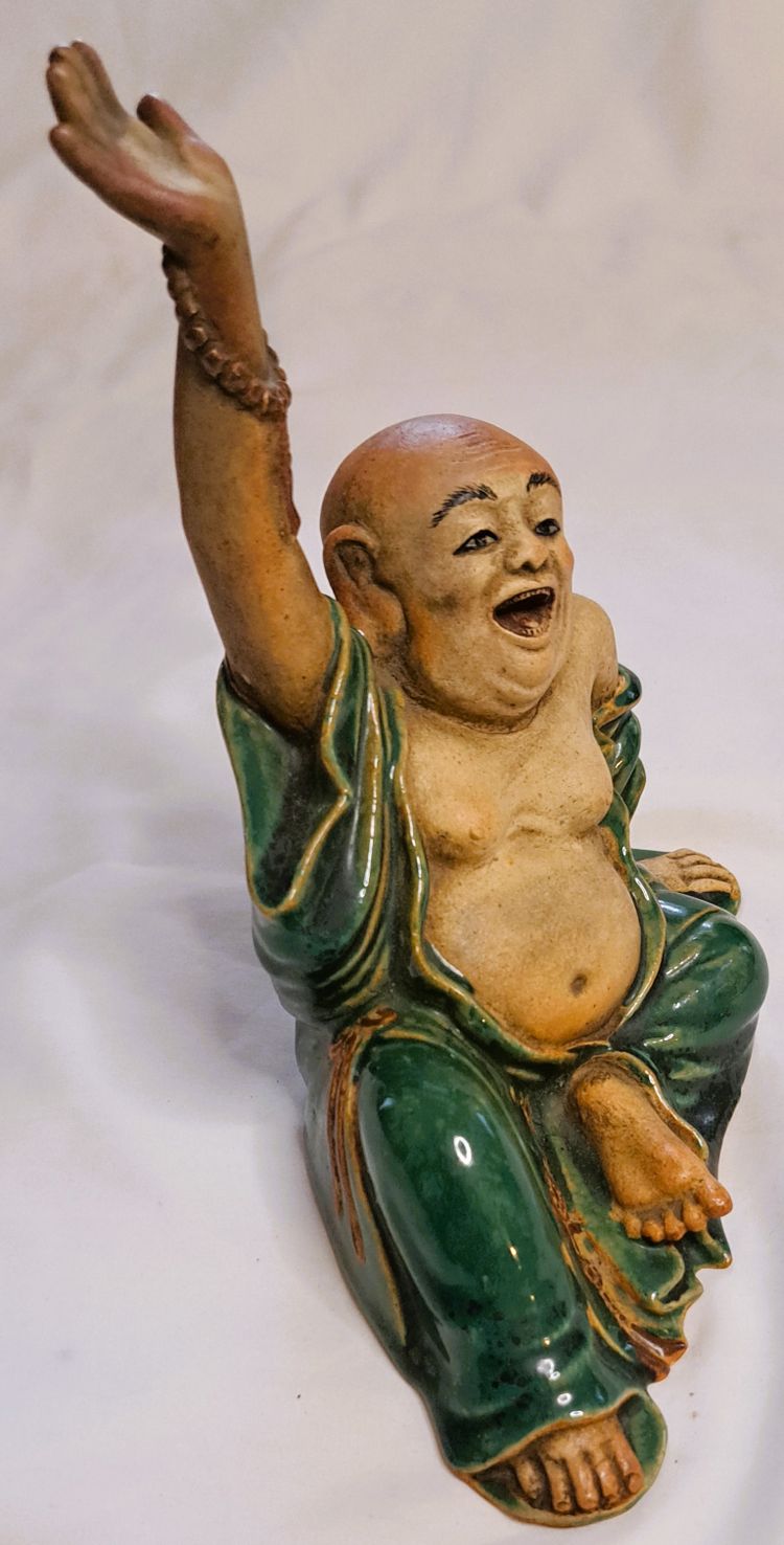 Antica statua di Buddha in terracotta con un braccio sollevato