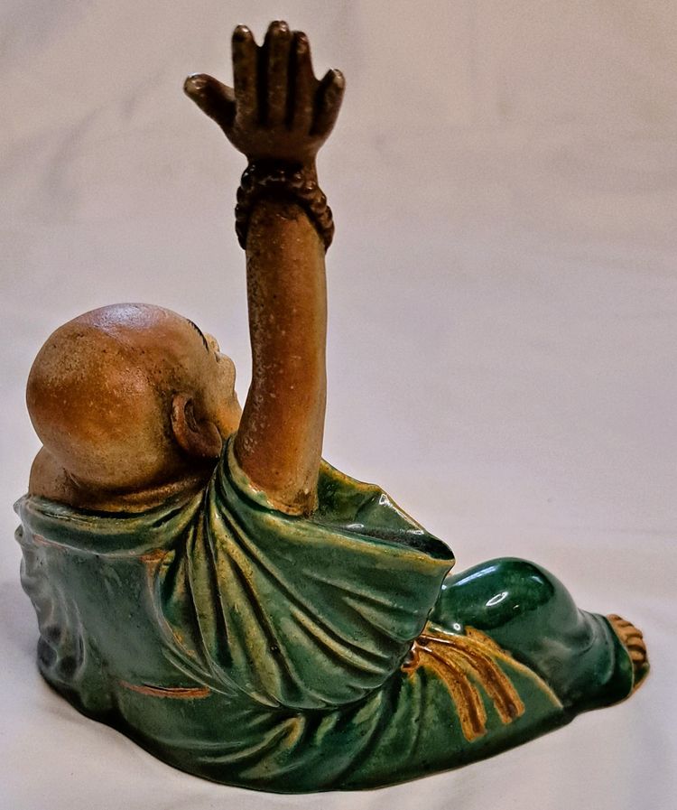 Antica statua di Buddha in terracotta con un braccio sollevato