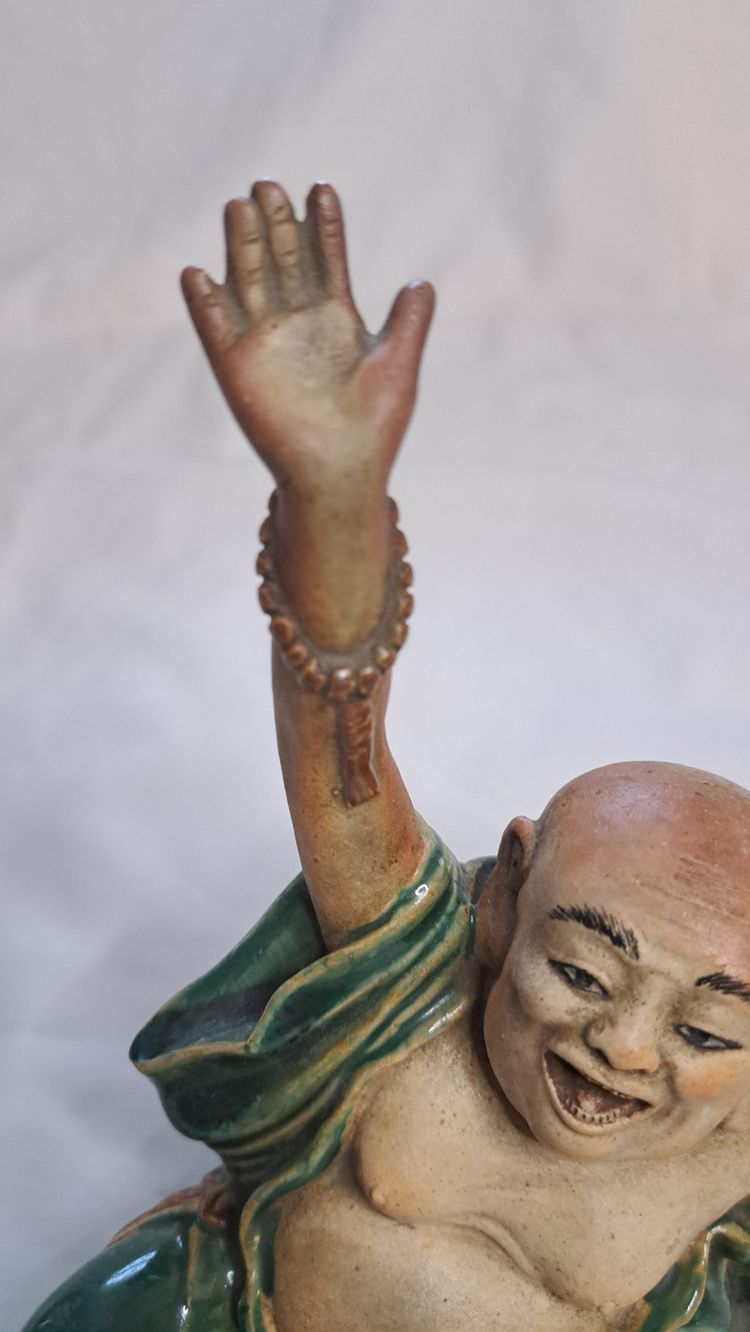 Antica statua di Buddha in terracotta con un braccio sollevato