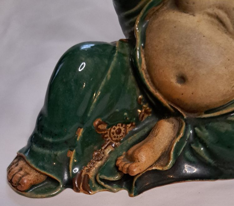 Antica statua di Buddha in terracotta con un braccio sollevato