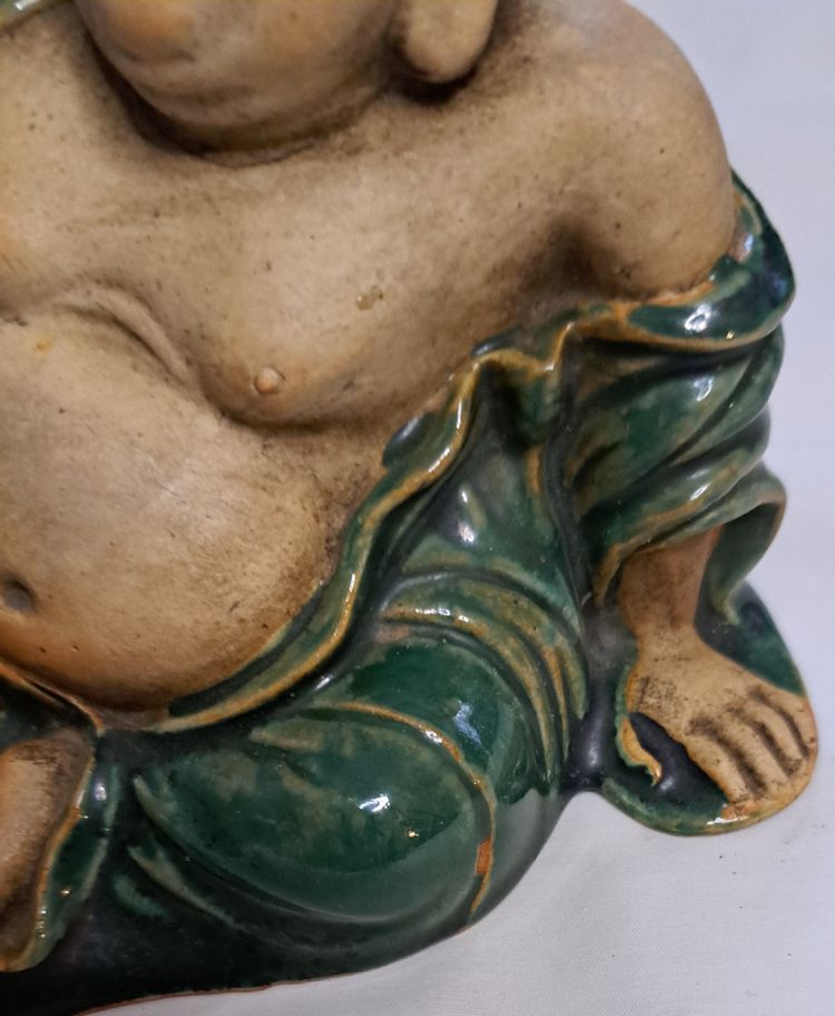 Antica statua di Buddha in terracotta con un braccio sollevato