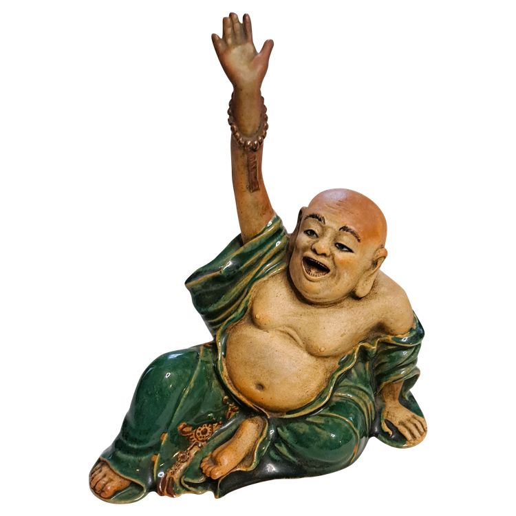 Antica statua di Buddha in terracotta con un braccio sollevato