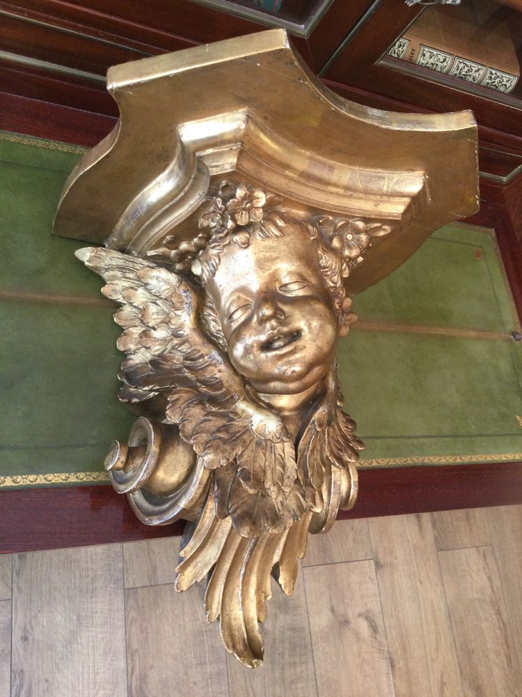 Une console murale en bois doré à tête d'angelot.