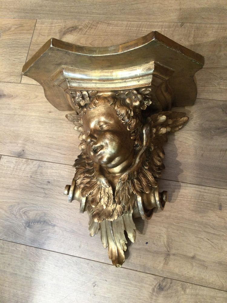 Une console murale en bois doré à tête d'angelot.