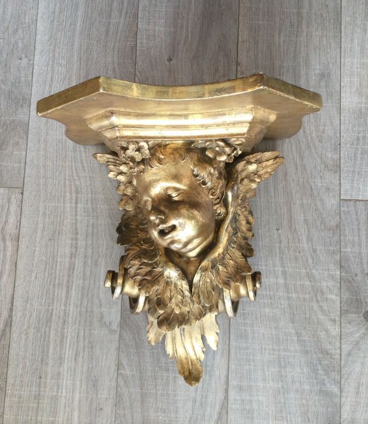 Une console murale en bois doré à tête d'angelot.