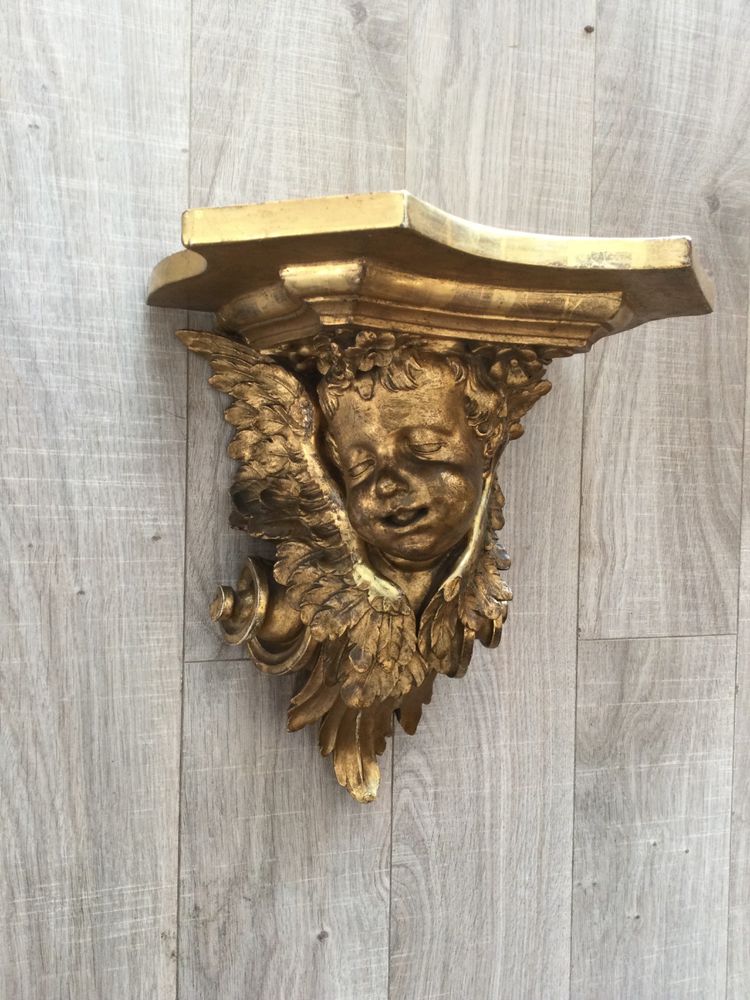 Une console murale en bois doré à tête d'angelot.