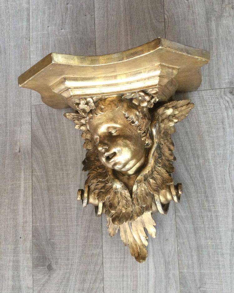 Une console murale en bois doré à tête d'angelot.