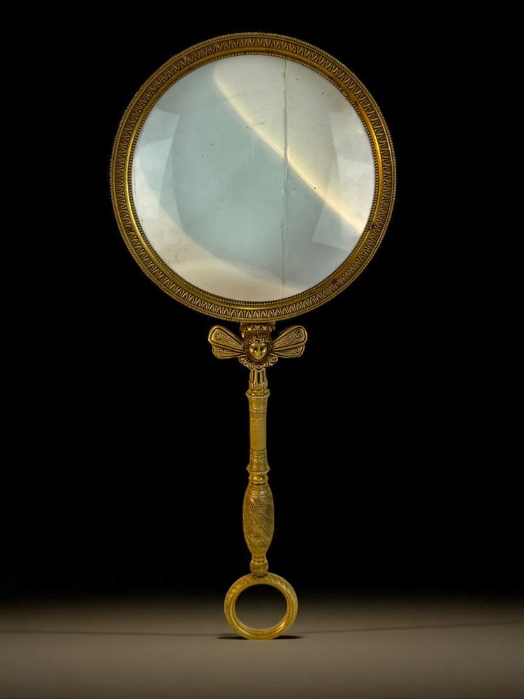 LARGE EMPIRE PERIOD MAGNIFYING GLASS IN CHASED AND GILDED BRONZE WITH WINGED FEMALE HEAD DECORATION