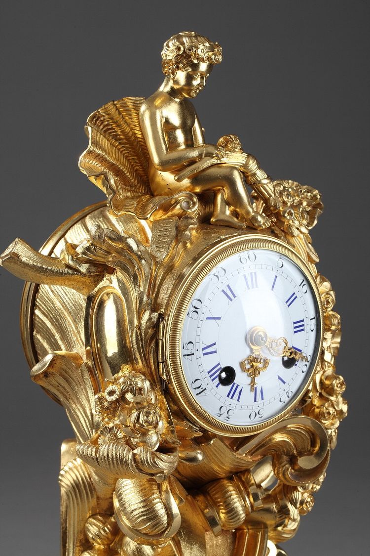 Pendule de style Rocaille en bronze doré, ornée d'un Amour dans une coquille