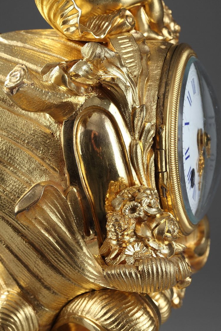 Pendule de style Rocaille en bronze doré, ornée d'un Amour dans une coquille