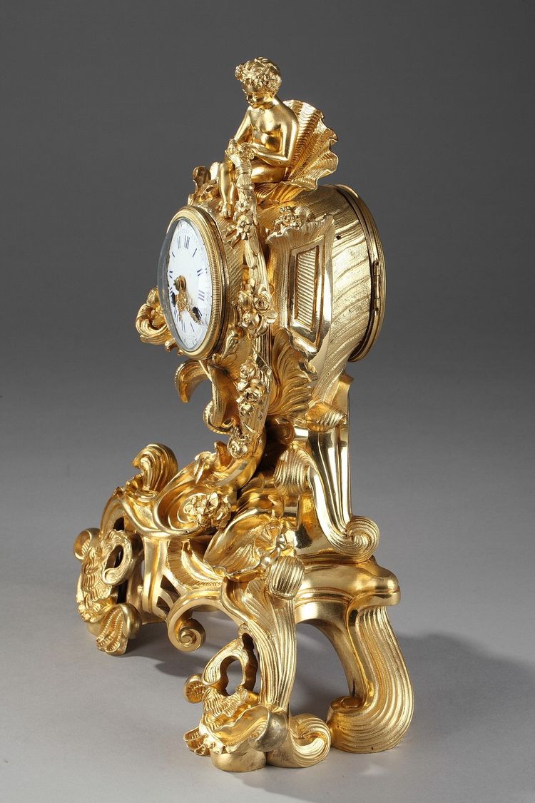 Pendule de style Rocaille en bronze doré, ornée d'un Amour dans une coquille