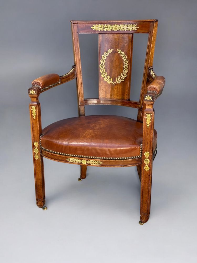 Empire-style armchair in walnut decorated with gilt bronze and covered in brown leather