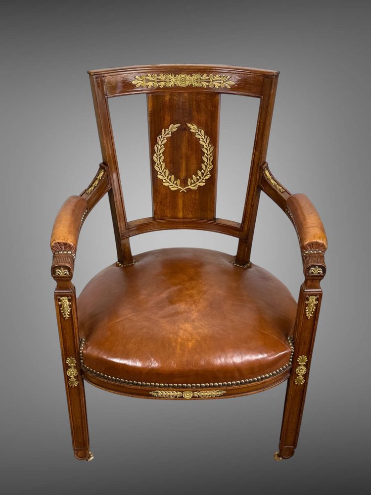 Empire-style armchair in walnut decorated with gilt bronze and covered in brown leather
