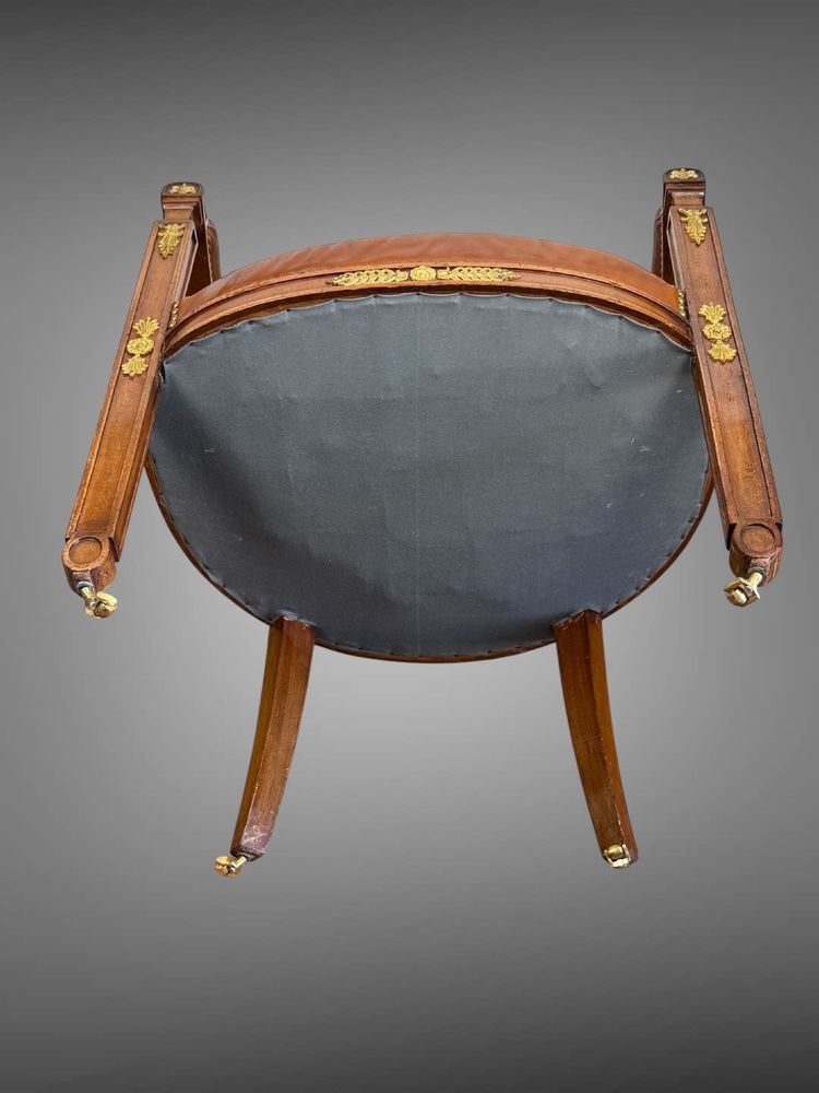 Empire-style armchair in walnut decorated with gilt bronze and covered in brown leather