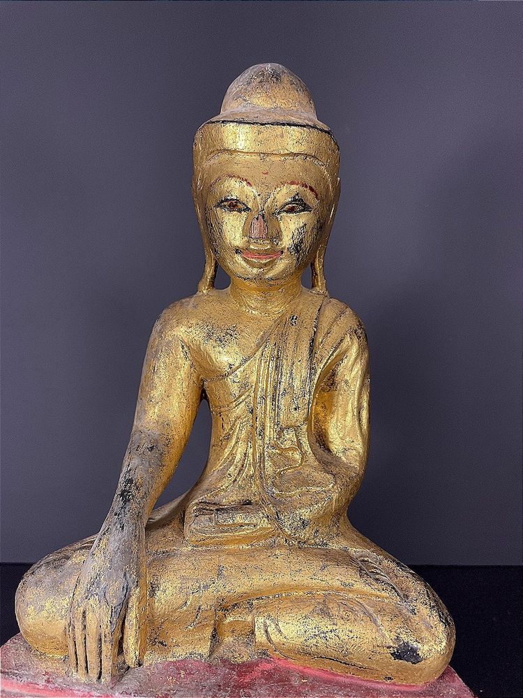 Birma, Mitte des 20. Jahrhunderts, rot und gold lackierte Holzskulptur, die einen sitzenden Buddha darstellt.