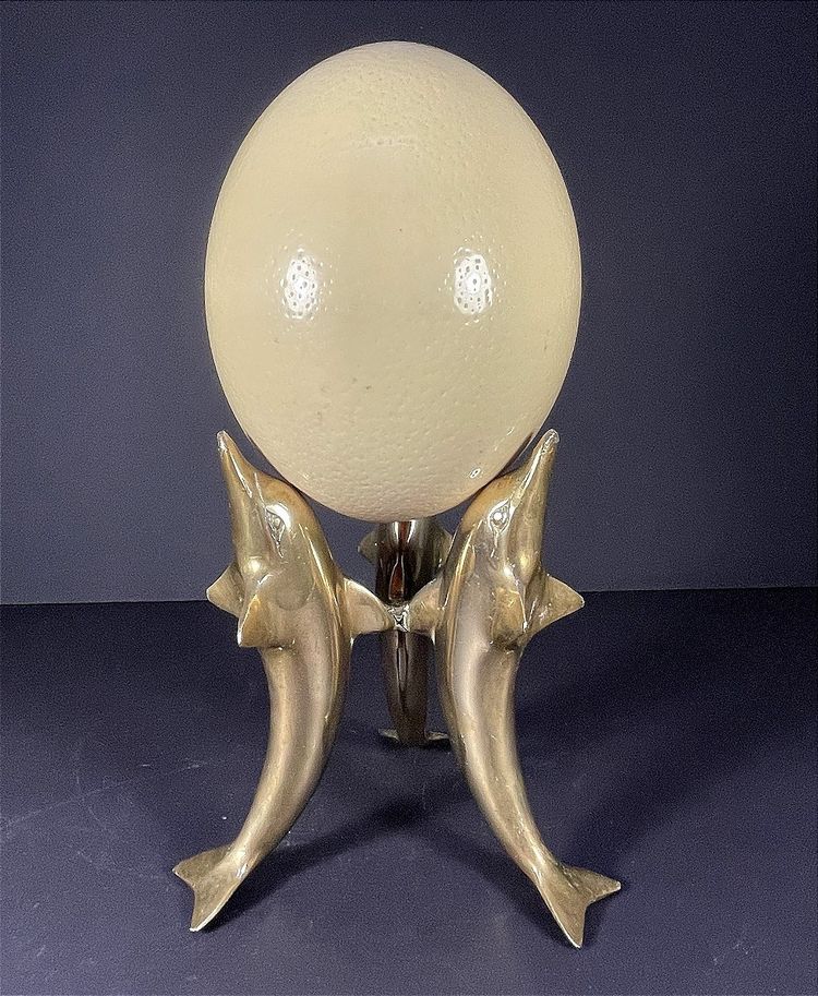 France, Ostrich egg mounted on a brass tripod base with a representation of dolphins, 1970.
