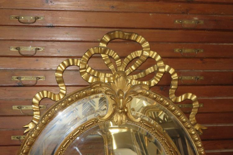 Grande specchio ovale con frontone, in legno dorato, XIX secolo.