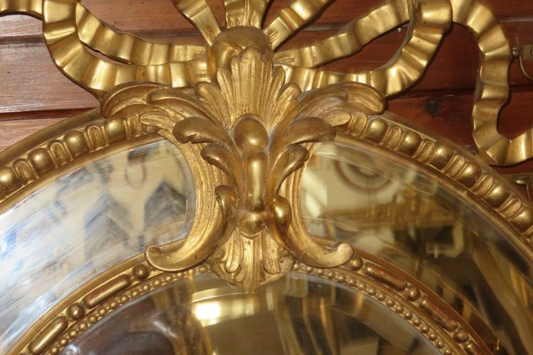 Grande specchio ovale con frontone, in legno dorato, XIX secolo.
