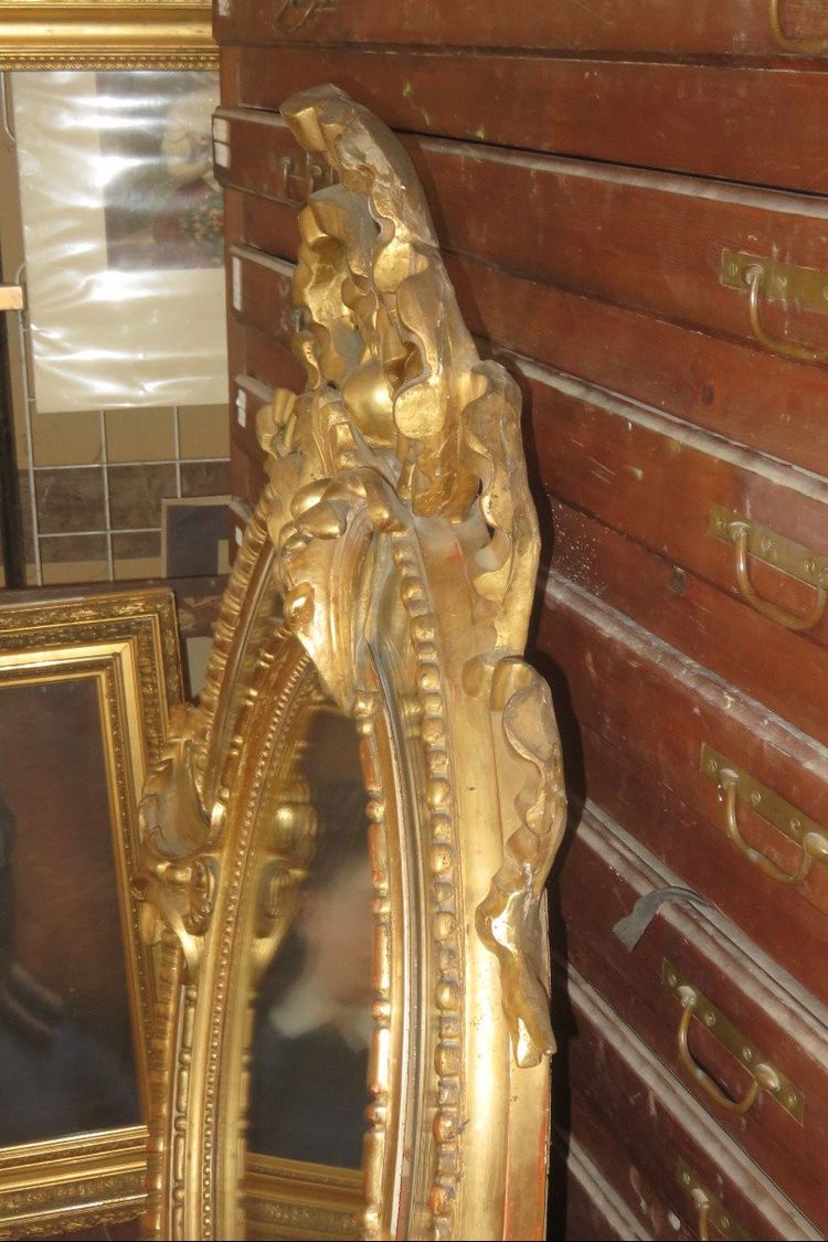 Grande specchio ovale con frontone, in legno dorato, XIX secolo.