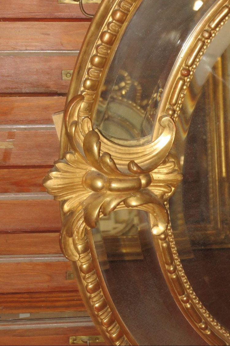 Grande specchio ovale con frontone, in legno dorato, XIX secolo.