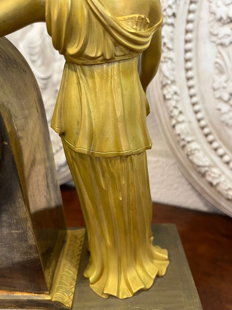 Pendule en bronze ciselé et doré à décor d’une femme à l’Antique et d’un Amour .