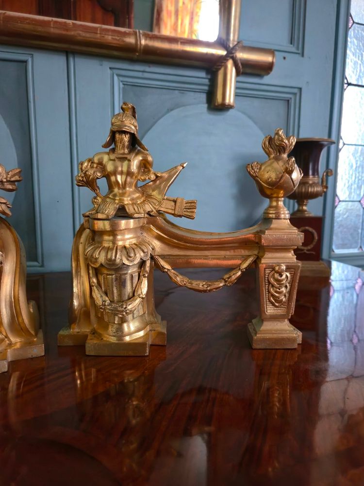 Paire de têtes de chenets aux trophées d'armes en bronze doré, transition Louis XV-Louis XVI