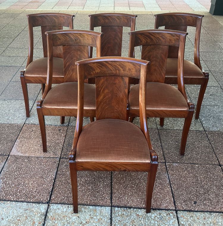 Six varnished mahogany chairs with curved backs.