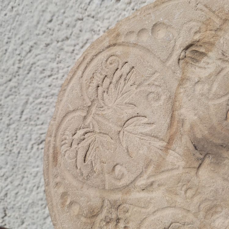 Round stone carved on each face, probably 17th century