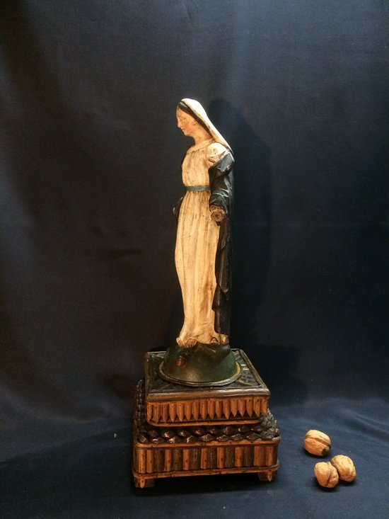 Vergine in legno intagliato su supporto in legno nero.