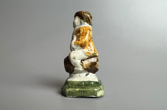 A c1790 Staffordshire pratt coloured pearlware toper figure seated on a barrel.