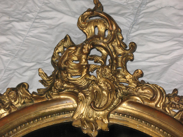 Carved oval mirror in wood and stucco gilded with leaf 19th century