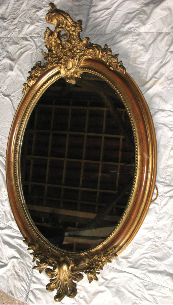 Carved oval mirror in wood and stucco gilded with leaf 19th century