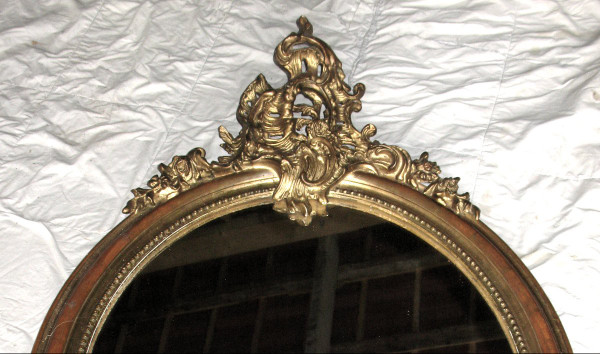 Carved oval mirror in wood and stucco gilded with leaf 19th century