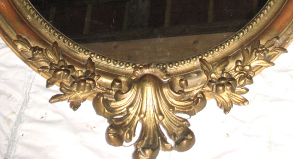 Carved oval mirror in wood and stucco gilded with leaf 19th century