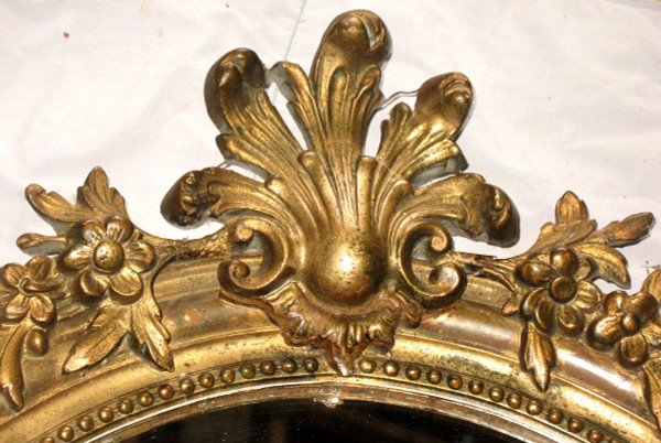 Carved oval mirror in wood and stucco gilded with leaf 19th century