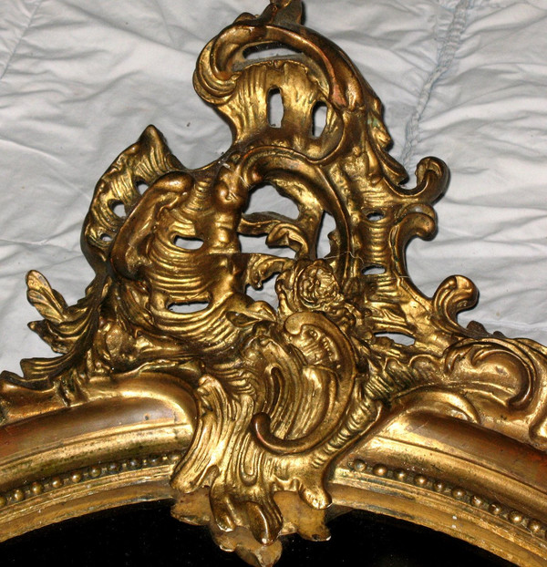 Carved oval mirror in wood and stucco gilded with leaf 19th century