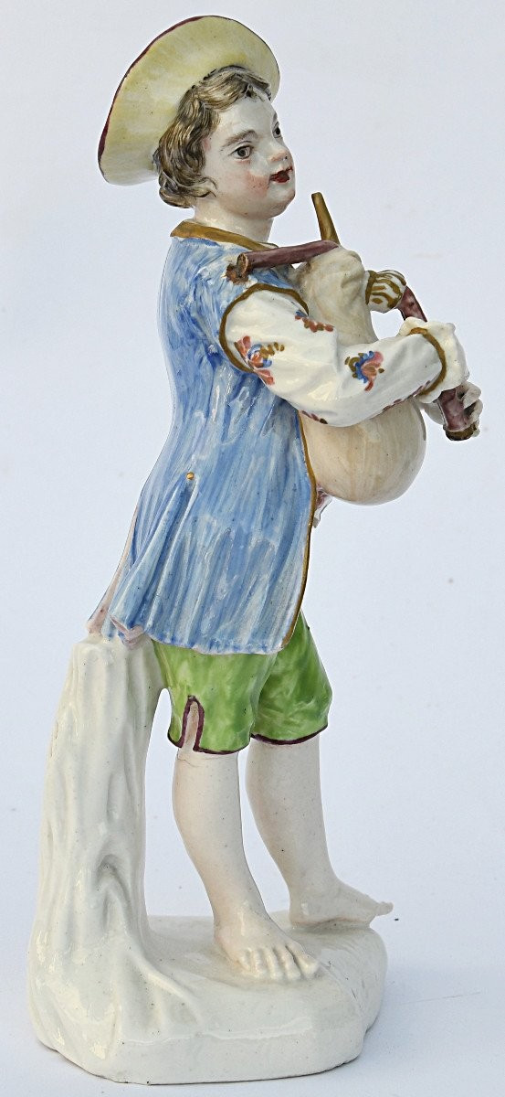 Statuette en porcelaine figurant un jeune garçon jouant de la cornemuse