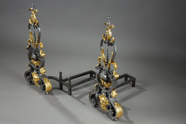Paire de landiers en fer forgé à décor feuillagé, masque et volutes