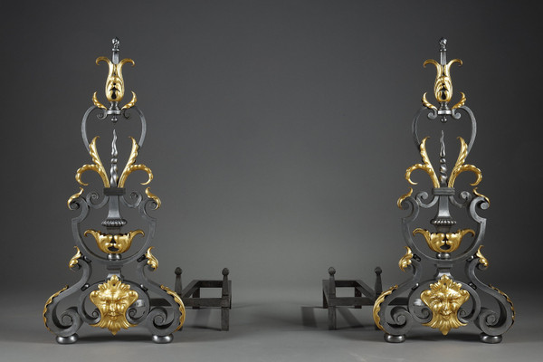 Paire de landiers en fer forgé à décor feuillagé, masque et volutes