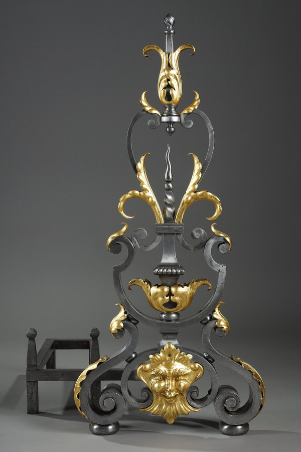 Paire de landiers en fer forgé à décor feuillagé, masque et volutes